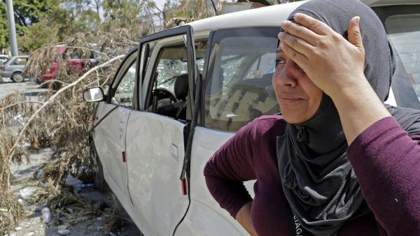Rima Zahed stands near a damaged car at the entrance of the port of Beirut as she awaits for news of her missing brother Mohammed, a port employee, on August 8, 2020. More than 60 people are still missing in Beirut, four days after a massive explosion at the port left more than 150 people dead, a health ministry official said today. ANWAR AMRO / AFP