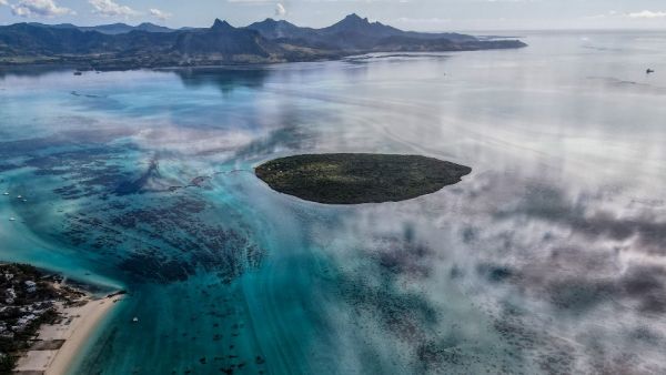 This aerial view taken on August 8, 2020 shows the Pointe d'Esny, and the Grand Port in the background, with a large patch of leaked oil and the vessel MV Wakashio, belonging to a Japanese company but Panamanian-flagged, that ran aground near Blue Bay Marine Park off the coast of south-east Mauritius. France on August 8, 2020 dispatched aircraft and technical advisers from Reunion to Mauritius after the prime minister appealed for urgent assistance to contain a worsening oil spill polluting the island natio