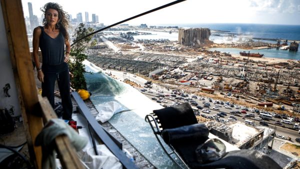 Karina Sukkar, a Lebanese architect and designer, stands the balcony of her damaged apartment overlooking the ravaged port of Lebanon's capital Beirut, in the neighbourhood of Mar Mikhael on August 9, 2020, in the aftermath of a colossal explosion that occurred days prior due to a huge pile of ammonium nitrate that had languished for years at a port warehouse. The huge chemical explosion that hit Beirut's port, devastating large parts of the Lebanese capital and claiming over 150 lives, left a 43-metre (141