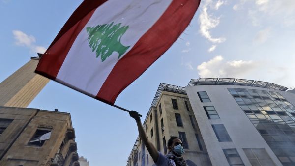 A Lebanese protester waves a national flag amid clashes with security forces in central Beirut on August 10, 2020. Lebanese Prime Minister Hassan Diab will announce his government's resignation imminently over the backlash from the deadly Beirut port explosion. JOSEPH EID / AFP
