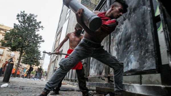 Lebanese protesters try to break through a barrier amid clashes with security forces in the vicinity of the parliament building in the centre of Beirut on August 11, 2020, following a huge explosion that devastated large parts of the capital. IBRAHIM AMRO / AFP