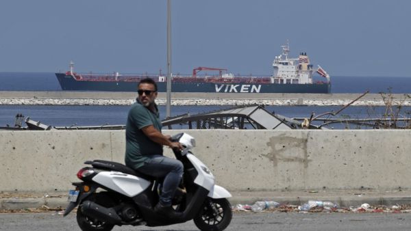 A motorcyclist rides across from the Kronviken crude oil tanker docked at the destroyed port of Beirut following a huge explosion that disfigured the Lebanese capital, on August 12, 2020. JOSEPH EID / AFP