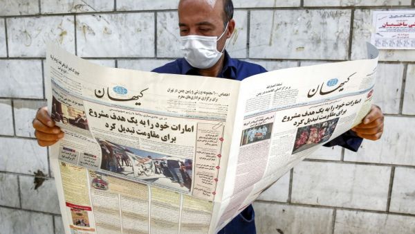 A man, clad in mask due to COVID-19 coronavirus pandemic, reads a copy of the Kayhan newspaper, considered to be the mouthpiece of ultraconservatives in Iran, with a headline on its front page reading in Farsi "the UAE has become legitimate and easy target for the resistance", while standing by a newspaper stall in Iran's capital Tehran on August 15, 2020. AFP