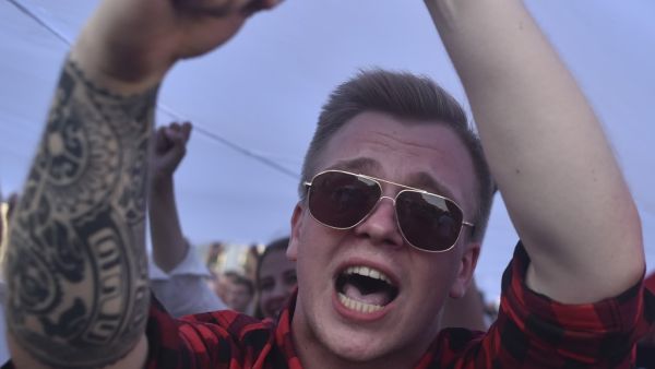 A Belarus opposition supporter shouts as he holds a giant former white-red-white flag of Belarus used in opposition to the government, during a demonstration in central Minsk on August 16, 2020. The Belarusian strongman, who has ruled his ex-Soviet country with an iron grip since 1994, is under increasing pressure from the streets and abroad over his claim to have won re-election on August 9, with 80 percent of the vote. Sergei GAPON / AFP