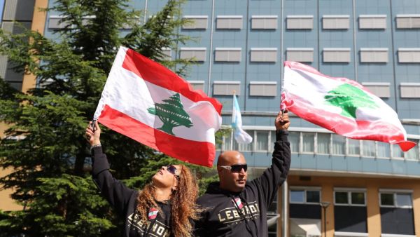 People gather and wave Lebanon national flags in front of the UN-backed Special Tribunal for Lebanon (STL) at Leidschendam on August 18, 2020, before the expected verdict on the 2005 murder of his father former Lebanese premier Rafic Hariri. KENZO TRIBOUILLARD / AFP