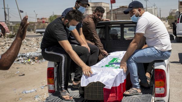 Mourners sit in the back of a vehicle by the Iraqi-flag draped coffin of slain activist Riham Yaaqub during her funeral in the centre of Iraq's southern city of Basra on August 20, 2020. Hussein FALEH / AFP