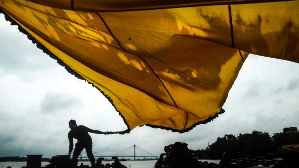 Muslims dry a traditional triangular flag for the upcoming Islamic festival 'Muharram' standing on an empty jetty near the Ganges river as the ferry service has been suspended during the first day of the two-day state-imposed lockdown as a preventive measure against the surge in COVID-19 coronavirus cases, in Kolkata on August 20, 2020. Dibyangshu SARKAR / AFP