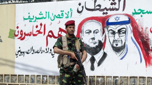 A fighter loyal to Yemen's Huthi rebels stands guard next to a mural denouncing Abu Dhabi Crown Prince Sheikh Mohammed bin Zayed Al Nahyan (R) and Israeli Prime Minister Benjamin Netanyahu, during a rally in the capital Sanaa, on August 22, 2020, to protest the US-brokered deal to normalise Emirati-Israeli relations. MOHAMMED HUWAIS / AFP