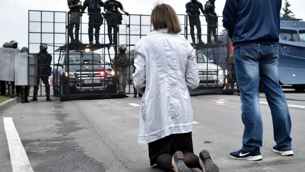 A demonstrator kneels in front of law enforcement officers blocking an area in front of the Independence Palace during a rally of opposition supporters to protest against disputed presidential election results in Minsk on August 23, 2020. Tens of thousands of demonstrators massed in central Minsk on August 23 to demand the resignation of Belarusian President Alexander Lukashenko, the latest in a wave of protests against his disputed re-election. Sergei GAPON / AFP
