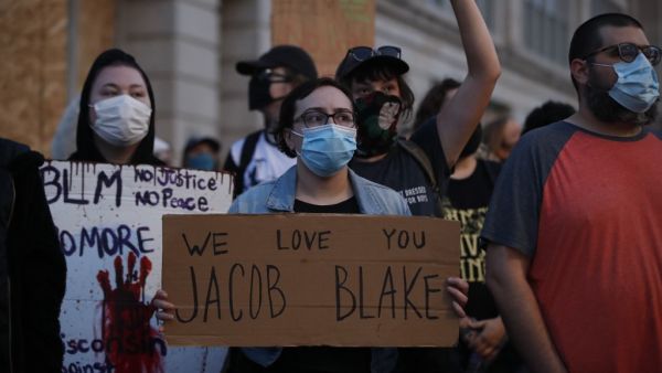 People hold signs as they march outside the County Courthouse during demonstrations against the shooting of Jacob Blake in Kenosha, Wisconsin on August 25, 2020. KAMIL KRZACZYNSKI / AFP