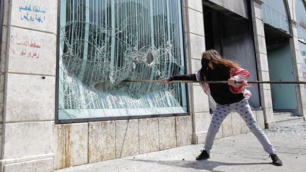 A Lebanese protester smashes the facade of a bank at Al-Nour square following the funeral of a fellow protester in Lebanon's northern port city of Tripoli, on April 28, 2020. Ibrahim CHALHOUB / AFP