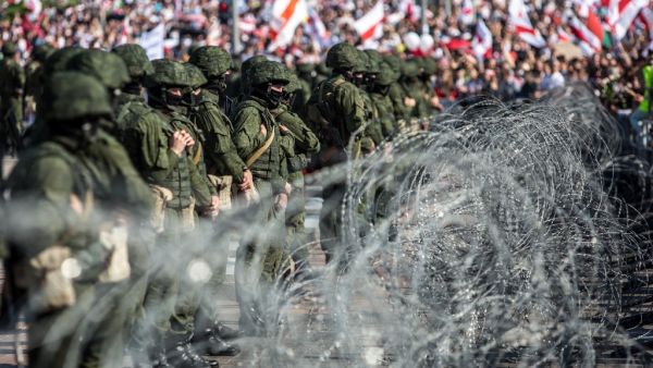 Belarusian servicemen stand behind a barbed wire fence during an opposition supporters rally protesting against disputed presidential elections results in Minsk on August 30, 2020. Tens of thousands of opposition supporters marched through Minsk on August 30, calling for an end to strongman Alexander Lukashenko's rule amid a heavy security presence and despite dozens of arrests. Belarus protests have entered a third week since the disputed presidential election on August 9 in which Lukashenko claimed victor
