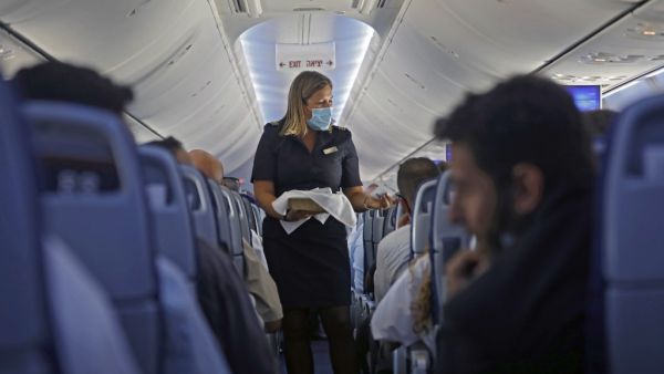A flight attendant hands out chocolates with a greeting card to passengers on an El Al plane from Israel en route to Abu Dhabi, on August 31, 2020. (AFP)