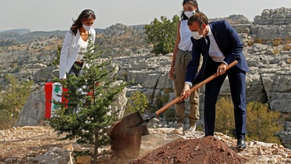 French President Emmanuel Macron (R) plants a cedar tree alongside members of the NGO Jouzour Loubnan during a ceremony marking Lebanon's centenary in Jaj Cedars Reserve Forest, northeast of the capital Beirut, on September 1, 2020. GONZALO FUENTES / POOL / AFP