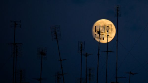 Television antennas atop a building are pictured against the moon on August 31, 2020 in Rome. Tiziana FABI / AFP