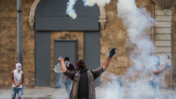 A protester uses a tennis racket to repel a tear gas canister during clashes with security forces amidst an anti-government demonstration in the centre of Lebanon's capital Beirut during on September 1, 2020. AFP
