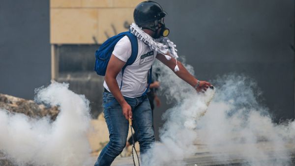 A protester uses a badminton racket to serve back a tear gas canister during clashes with security forces amidst an anti-government demonstration in the centre of Lebanon's capital Beirut during on September 1, 2020. AFP