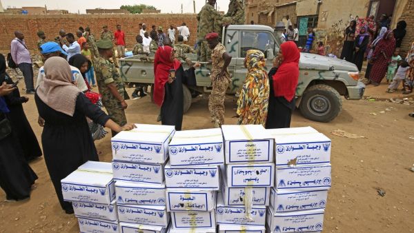 Sudanese people and security forces stand near boxes of aid at a region affected by flood in Tuti island, where the Blue and White Nile merge between the twin cities of the capital Khartoum and Omdurman, on September 3, 2020. ASHRAF SHAZLY / AFP