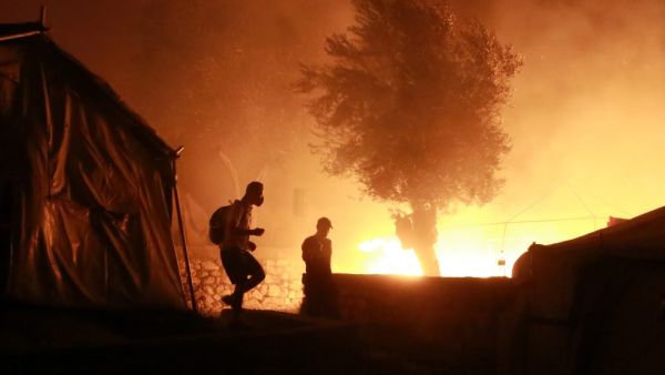 Migrants walk inside the Moria camp on the island of Lesbos during a major fire there on September 9, 2020. Manolis LAGOUTARIS / AFP