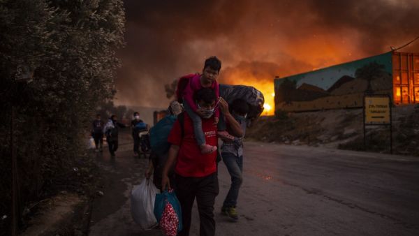 People with children flee flames after a major fire broke out in the Moria migrants camp on the Greek Aegean island of Lesbos, on September 9, 2020. ANGELOS TZORTZINIS / AFP