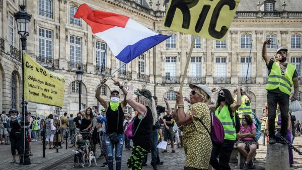 A protester holds a sign reading "RIC" for "Citizens Initiative Referendum" and another wave a French national flag as they take part in a demonstration called by the "Yellow Vest" (Gilets Jaunes) movement in Bordeaux, southwestern France on September 12, 2020. Philippe LOPEZ / AFP