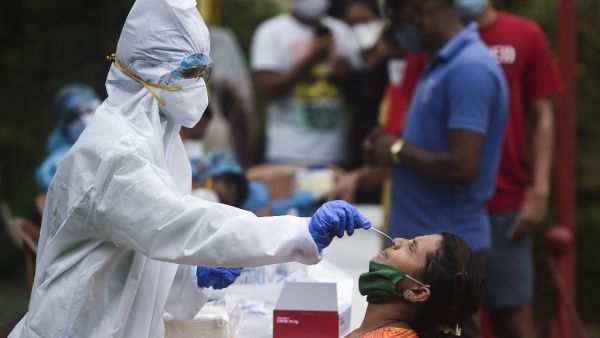 A medical staff wearing Personal Protective Equipment (PPE) takes a nasal swab sample from a resident for a Covid-19 Coronavirus test, in a residential area in Mumbai, on September 14, 2020. Punit PARANJPE / AFP