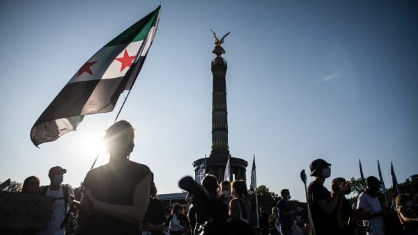 A protester holds an old Syrian flag during a demonstration for the evacuation of all migrant camps in Greece after the fire at the Moria refugee camp on Lesbos, on September 20, 2020 in Berlin. STEFANIE LOOS / AFP