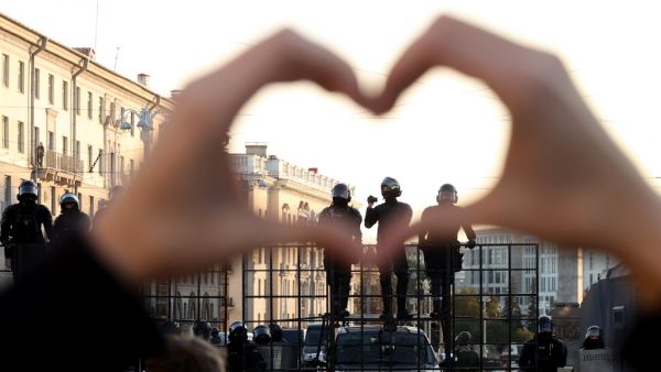 A woman gestures making a heart shape as she stands in front of law enforcement officers blocking the road during a demonstration called by opposition movement for an end to the regime of authoritarian leader in Minsk on September 20, 2020. Belarus President Alexander Lukashenko, who has ruled the ex-Soviet state for 26 years, claimed to have defeated opposition leader Svetlana Tikhanovskaya with 80 percent of the vote in the August 9, elections. STRINGER / AFP