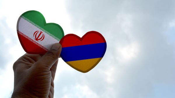 Hand holds a heart Shape Iran and Armenia flag, love between two countries  (Shutterstock)