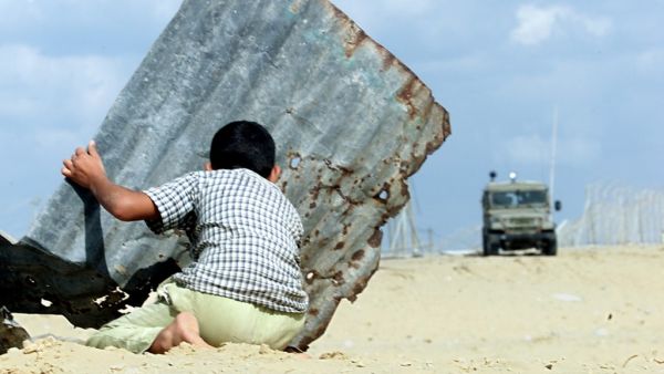 In this file photo taken on October 24, 2000, a Palestinian child takes cover behind a sheet of corrugated iron during clashes in Khan Yunes in the Gaza Strip. THOMAS COEX / AFP