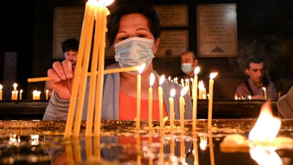 A woman lights a candle during a Sunday service in Yerevan's Saint Sarkis church on October 4, 2020. AFP