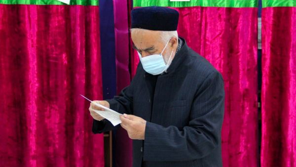 A man looks through his ballot at a polling station during Tajikistan's presidential election in Dushanbe on October 11, 2020, amid the ongoing coronavirus disease pandemic. STRINGER / AFP
