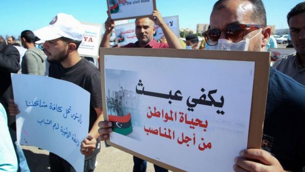 Libyans lift placards making demands on participants in talks between the country’s two rival administrations, in front of the headquarters of the UN Mission, in the city of Janzour, west of the Libyan capital, October 14. (AFP)