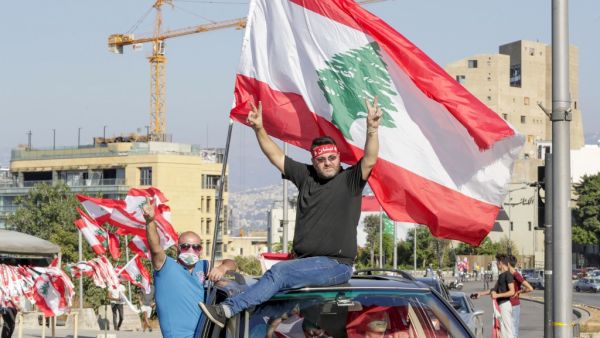 Lebanese demonstrators wave the national flag as they drive to a demonstration, marking the first anniversary of a non-sectarian protest movement, in the capital Beirut's downtown area on October 17, 2020. (AFP/File)