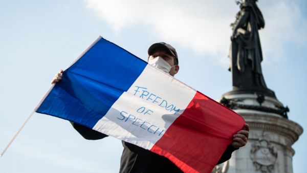 A man holds a French flag as people gather on Place de la Republique in Paris on October 18, 2020, in homage to history teacher Samuel Paty two days after he was beheaded by an attacker who was shot dead by policemen. BERTRAND GUAY / AFP