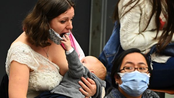 A woman breastfeeds her child, that jokes with her face mask, during the Pope Francis' weekly general audience at Paul VI hall on October 21, 2020, at the Vatican. Vincenzo PINTO / AFP