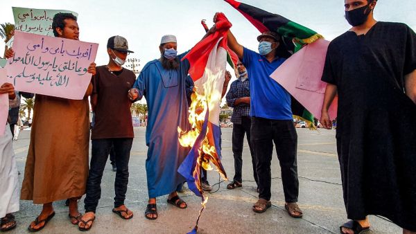 Demonstrators set fire to a French national flag during a rally protesting against the comments of French President Emmanuel Macron over Prophet Mohammed cartoons, at the Martyrs' Square of Libya's capital Tripoli on October 25, 2020. Mahmud TURKIA / AFP