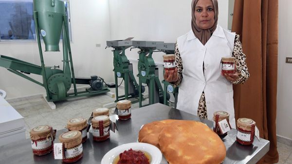 The manager of a cooperative for making harissa paste poses boxes of the produce in  Menzel Mehiri in Kairouan governorate some 200 kilometres south of Tunis. (AFP)