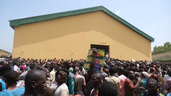 People carry bags of food on their heads during a mass looting of a warehouse in Abuja on Monday. (AFP)