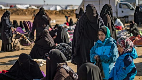 Women and children sit outdoors on the ground at the Kurdish-run al-Hol camp for the displaced in Hasakah province in northeastern Syria on Jan. 14, 2020, where families of Islamic State fighters are held. Photo by Photo by DELIL SOULEIMAN/AFP via Getty Images.