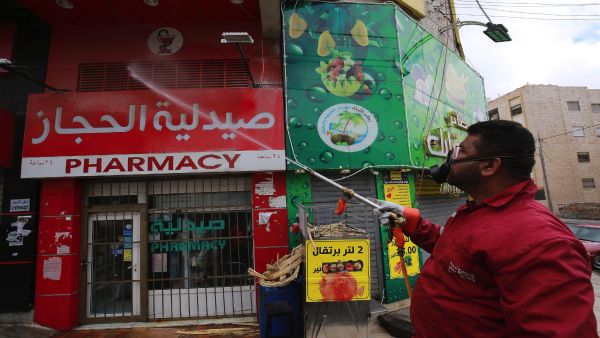 A municipality worker disinfects a pharmacy in the Jordanian capital Amman as part of preventive measures against the spread of the coronavirus, on March 21, 2020. Photo by Photo by KHALIL MAZRAAWI/AFP via Getty Images.