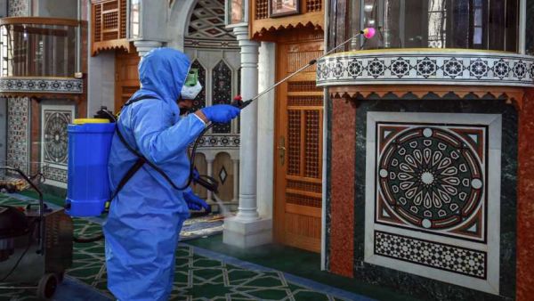 A Worker dressed in personal protective equipment sterilizes the mihrab of a mosque in Jordan's capital Amman on June 3, 2020, ahead of its reopening. Photo File by KHALIL MAZRAAWI/AFP via Getty Images. 