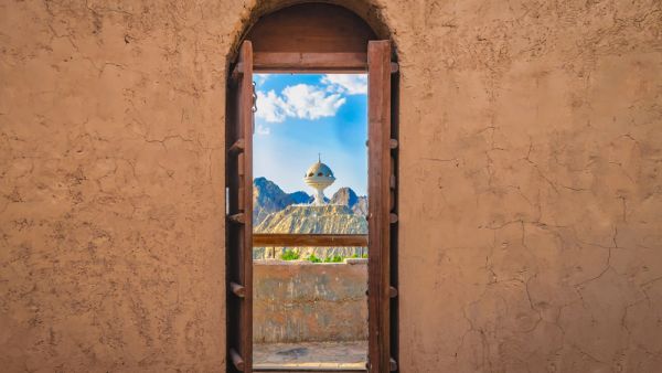 Narrow archway with old, heavy wooden doors opened to show the famous frankincense monument of Muscat, Oman  (Shutterstock)	