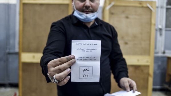A poll station worker displays a cast "yes" ballot during the counting after a vote on a revised constitution ended at a station in Algeria's capital Algiers on November 1, 2020. RYAD KRAMDI / AFP