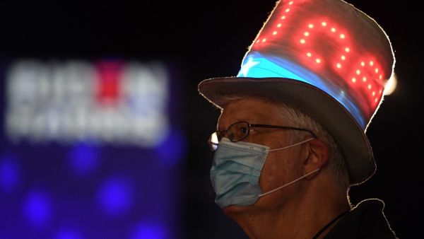 A supporter of Democratic presidential nominee and former Vice President Joe Biden looks at partial election results on a giant screen outside the Chase Center in Wilmington, Delaware on the early hours of November 4, 2020. Roberto SCHMIDT / AFP