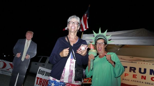 Supporters of US President Donald Trump, Carol Sievers (L) and Pamela Morgan, cheer near a Trump cardboard cutout at Bob Ruud Community Center on Election Day, November 3, 2020, in Pahrump, Nevada. Ronda Churchill / AFP