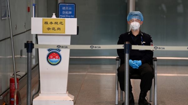 A security guard watches over the empty international arrivals channel at Beijing airport on November 6, 2020, after China banned foreign arrivals from France and a host of other countries, the latest in a growing number of entry bans as China closes itself off from a world still battling the coronavirus pandemic. GREG BAKER / AFP