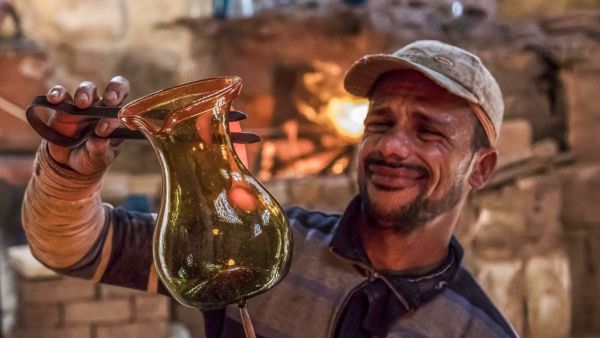 A glassblower sculpts a vessel at a workshop near the 15th century Sultan Qaitbay mosque complex in the "Desert of the Mamluks" (City of the Dead) area of Egypt's capital Cairo on November 1, 2020. In Egypt's "City of the Dead", centuries-old monuments are being restored and artisanal heritage revived, turning a corner of the vast historical cemetery into a vibrant neighbourhood full of life. Since 2014, a series of projects financed by the European Union has changed the face of this small section of the sp