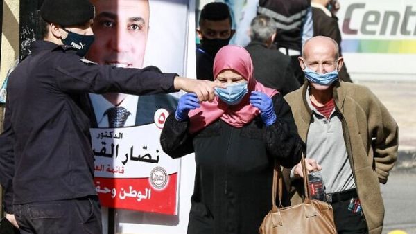 A member of the Jordanian security forces directs voters outside a polling station in Jordan’s capital Amman on November 10, 2020, during the 2020 general election. (Khalil MAZRAAWI/AFP)