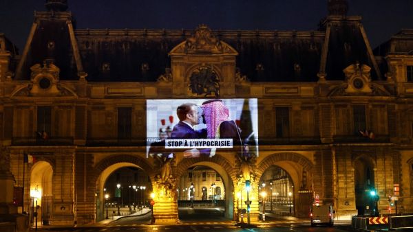 This picture taken early on November 19, 2020, shows a projection on the Louvre Museum in Paris by Amnesty International members depicting French President Emmanuel Macron greeting Saudi Crown Prince Mohammed bin Salman and reading "Stop hypocrisy", ahead of the upcoming virtual G20 summit. THOMAS COEX / AFP